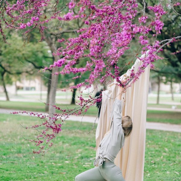 Child balancing in a tree yoga pose in a park setting.