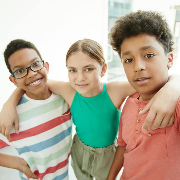 Group of diverse children doing yoga together and smiling.