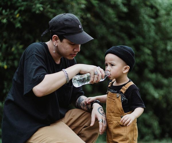 Parent helping a child pack a small bag with a water bottle.